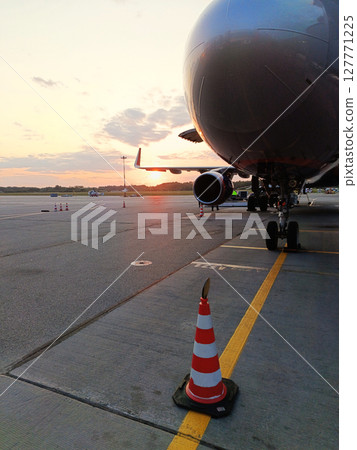 An airplane is currently parked on the runway right next to a traffic cone 127771225