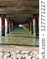 View of ocean under pier with sandy beach in the foreground 127771227