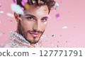 Close-up portrait of young man with glitter makeup and sequin outfit looking at camera with falling confetti on pink background. Studio shot with soft lighting. LGBT pride, queer identity, and self 127771791
