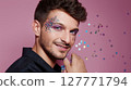 Smiling young man with glitter makeup on pink background posing with confident expression. Studio portrait with colorful sparkles. LGBT pride, queer identity, and self-expression concept. Design for 127771794