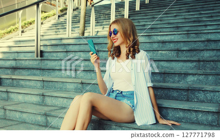 Stylish modern happy smiling young woman with phone in city park, girl holding smartphone on street 127771798