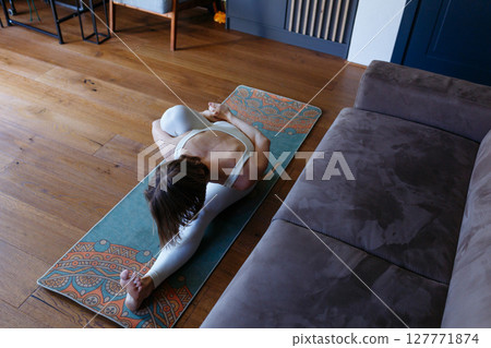 high angle view of a woman stretching legs at home doing yoga 127771874