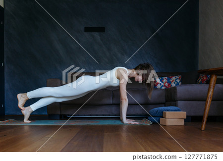 woman doing plank yoga pose at home 127771875