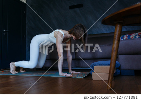 a woman doing table top yoga pose at home 127771881