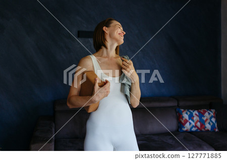 portrait of smiling woman holding towel and yoga brick after exercising at home portrait of smiling woman holding towel and yoga brick after exercising at home 127771885