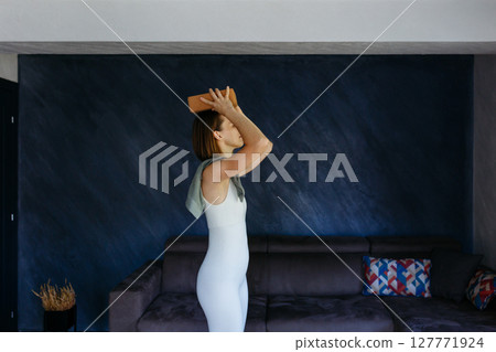 side view of woman putting balancing yoga block on her head side view of woman putting balancing yoga block on her head 127771924