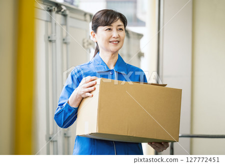 物流倉庫內搬運紙箱的中年婦女 物流倉庫內搬運紙箱的中年婦女 127772451