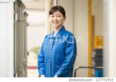 一名 50 多歲、身穿工作服的女性在倉庫工作 一名 50 多歲、身穿工作服的女性在倉庫工作 127772453