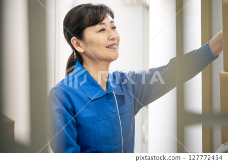一位身穿工作服的中年婦女在物流倉庫工作 127772454