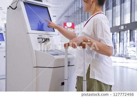 Woman self-checking in at airport 127772498