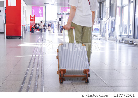 Traveler woman walking through airport lobby 127772501