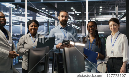 Happy data center engineering team members collaborating on neural network software development. Smiling server hub coworkers implementing machine learning technology in workplace, camera A 127772507