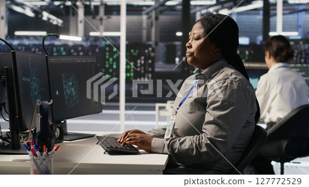 Annoyed data center employee making rude hand gesture toward colleague during workplace disagreement. Upset woman in server hub being dismissive to coworker during dispute, camera A Annoyed data center employee making rude hand gesture toward colleague during workplace disagreement. Upset woman in server hub being dismissive to coworker during dispute, camera A 127772529