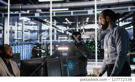 Upset data center worker packing personal items at workstation after being replaced by AI. Programmer removing belongings from server hub workplace desk, fired by artificial intelligence, camera A 127772536