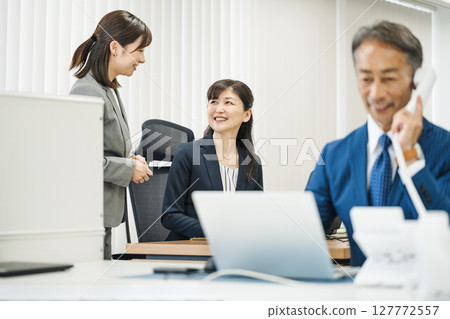 A female manager talking to her subordinate in the office 127772557