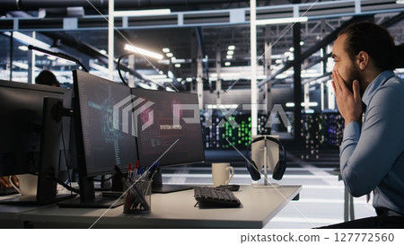 Employee requesting help from manager to fix hacked equipment systems. Stressed data center admin reacting to spyware popup on computer screen, launching emergency response protocol, camera A Employee requesting help from manager to fix hacked equipment systems. Stressed data center admin reacting to spyware popup on computer screen, launching emergency response protocol, camera A 127772560