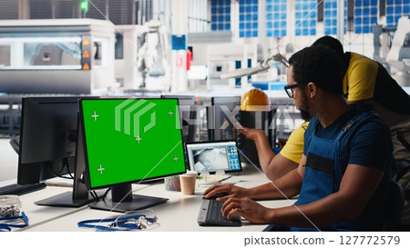 African american male engineer does troubleshooting on copy space display, fixing errors to ensure seamless solar panels manufacturing. Technician works in the assembly line. Camera B. 127772579