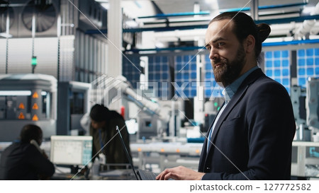 Solar panels industry technician in a high tech factory for inspection, quality control production metrics. Professional engineer ensuring industrial operations for efficiency. Camera A. 127772582