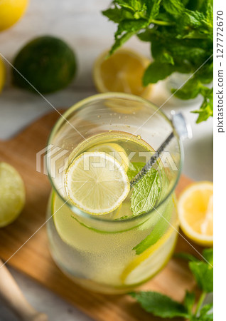 A glass jug with lemonade with lemons, limes and fresh mint, summer drink A glass jug with lemonade with lemons, limes and fresh mint, summer drink 127772670
