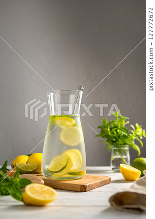 A glass jug with lemonade with lemons, limes and fresh mint, summer drink 127772672