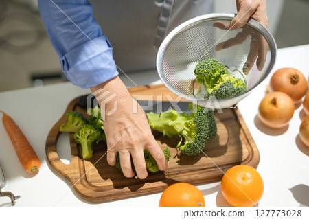 Hands of a middle-aged woman cutting vegetables Hands of a middle-aged woman cutting vegetables 127773028