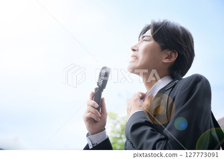 A busy businessman working in the heat - Cooling off with a handheld fan 127773091