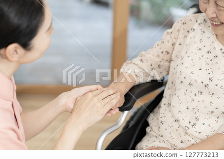 Female caregiver talking to a senior woman in a wheelchair Body parts Handshake Holding hands Communication Female caregiver talking to a senior woman in a wheelchair Body parts Handshake Holding hands Communication 127773213
