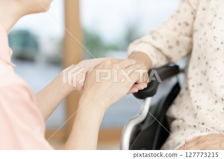Female caregiver talking to a senior woman in a wheelchair Body parts Handshake Holding hands Communication Female caregiver talking to a senior woman in a wheelchair Body parts Handshake Holding hands Communication 127773215