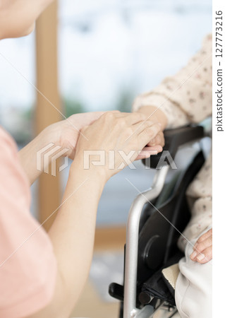 Female caregiver talking to a senior woman in a wheelchair Body parts Handshake Holding hands Communication 127773216