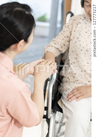 女性照護人員與坐輪椅的老年婦女交談身體部位握手握手溝通 女性照護人員與坐輪椅的老年婦女交談身體部位握手握手溝通 127773217