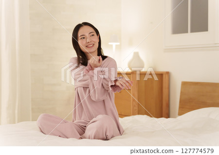 Woman stretching in bed at night Woman stretching in bed at night 127774579
