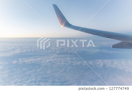 Beautiful salmon dawn and the wing of an airplane above the clouds. 127774749