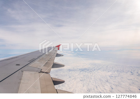 View from the airplane window at a beautiful cloudy sky and the airplane wing 127774846