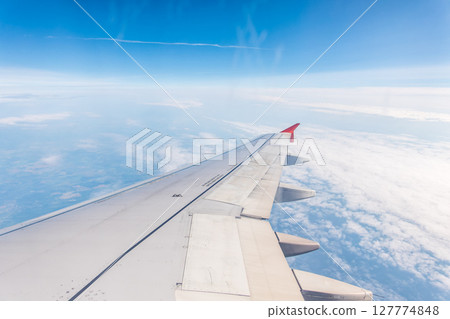 View from the airplane window at a beautiful cloudy sky and the airplane wing View from the airplane window at a beautiful cloudy sky and the airplane wing 127774848