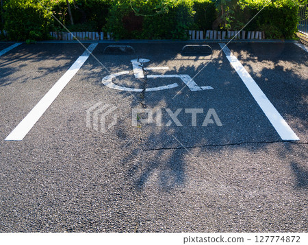 A parking space with a wheelchair symbol illuminated by sunlight 127774872