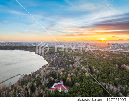 Autumn forest on lake shore at sunset and city on horizon, aerial view Autumn forest on lake shore at sunset and city on horizon, aerial view 127775005