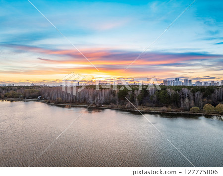 Colorful autumn forest with trees on the shore of a blue lake - top aerial view. Colorful autumn forest with trees on the shore of a blue lake - top aerial view. 127775006