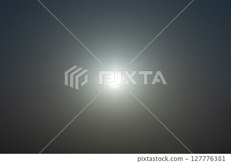 The sun shining in the sky, the flare reflected in it 127776381