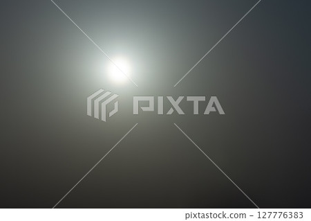 The sun shining in the sky, the flare reflected in it 127776383