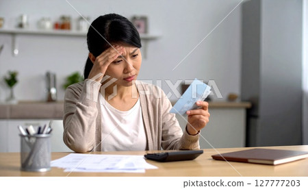 一位女士看著她的存摺，憂心忡忡 127777203