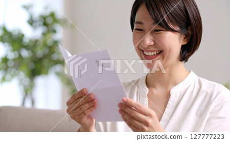 Illustration of a smiling woman looking at her bankbook 127777223