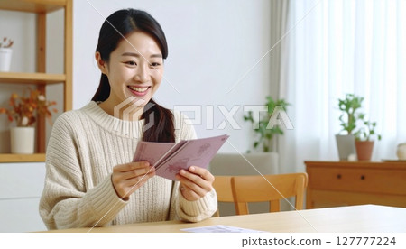 Illustration of a smiling woman looking at her bankbook Illustration of a smiling woman looking at her bankbook 127777224