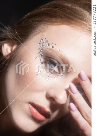 Beautiful woman portrait with glued jewelry on her face 127778221