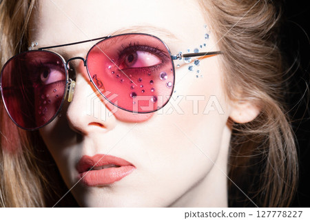Woman with sunglasses and glued jewelry close-up studio portrait Woman with sunglasses and glued jewelry close-up studio portrait 127778227