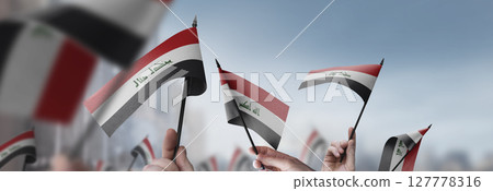 Iraq flags in their hands on a blurred urban background 127778316
