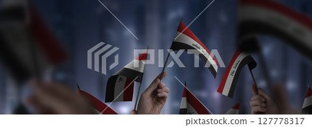 Iraq flags in their hands on a blurred urban background 127778317