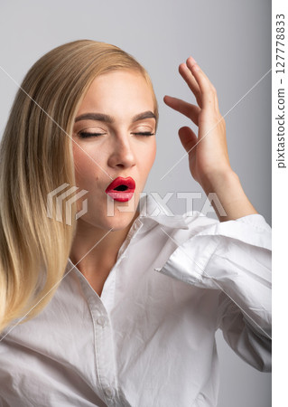 Beautiful blonde woman with long hair and red lipstick close-up studio portrait 127778833