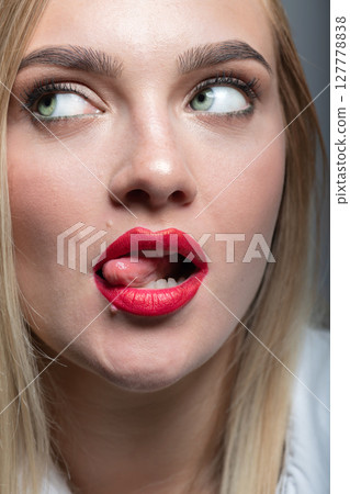 Beautiful woman with tongue sticking out looking aside the camera 127778838