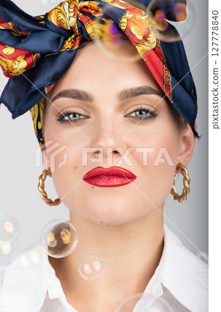 Portrait of beautiful woman with scarf on her head and flying soap bubbles Portrait of beautiful woman with scarf on her head and flying soap bubbles 127778840