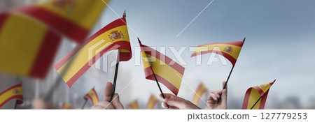 Spain flags in their hands on a blurred urban background 127779253